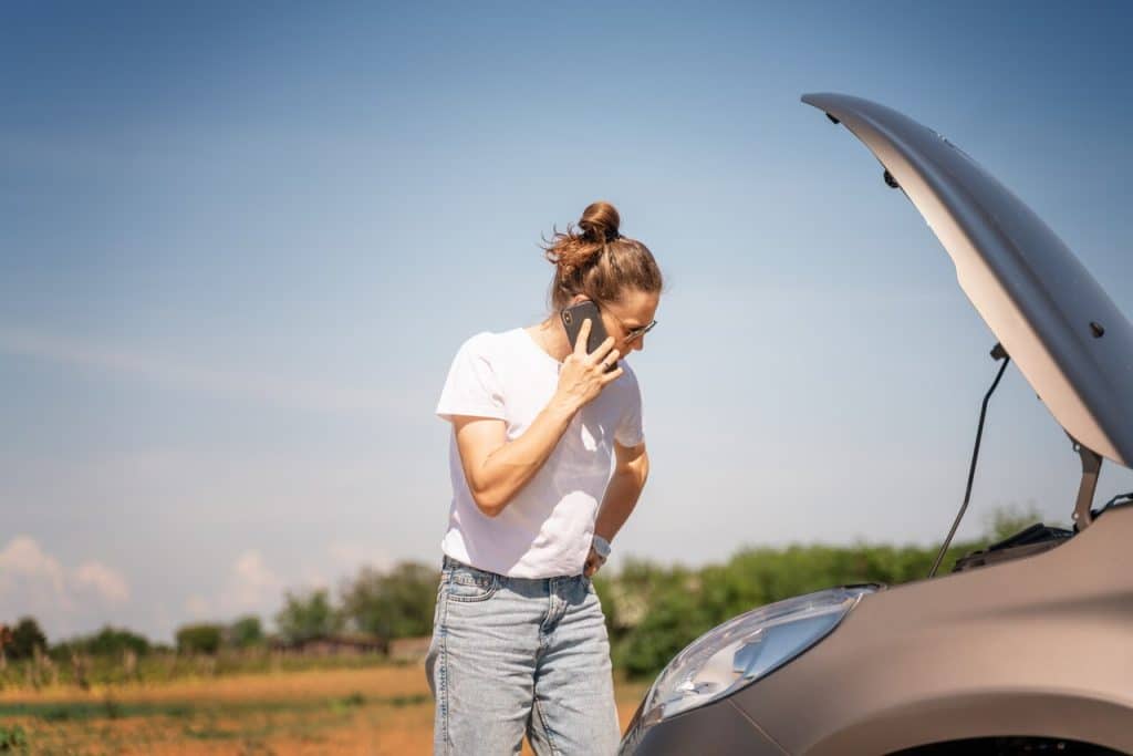 Araba Yolda Kalınca Ne Olur? 2 kaputu acik bir arac ve telefonda konusan bir kadin